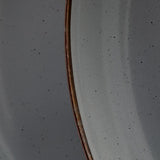 A close up of the enamel showing the black speckles and the metal rim with its vintage-looking distressed texture.