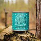 An up-close image of the candle sitting on a log in the woods