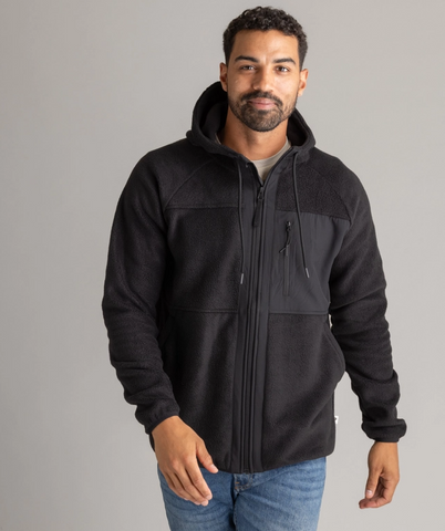 Man wearing a black hooded jacket in front of a grey background