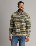Man wearing a patterned pullover standing in front of a grey background