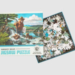 The puzzle box sits on a white background with the lid off, revealing all of the pieces inside the box. The lid is off to the side and shows the puzzle image of Smokey Bear and the cubs by the lake.